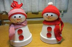 two snowmen wearing red hats and scarves on top of a wooden table next to each other