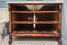 a bathroom with a sink, toilet and wooden cabinet in the middle of the floor