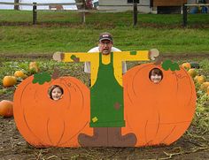 a man sitting in front of a fake pumpkin with two children on it's back