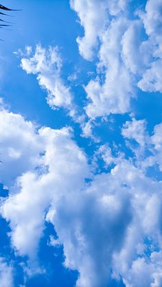 an airplane is flying in the sky with white clouds and blue sky behind it,