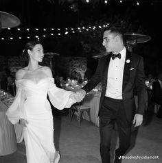 a bride and groom hold hands as they walk down the dance floor at their wedding reception