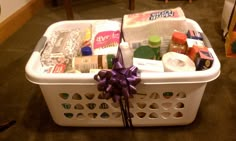 a white basket filled with lots of items on top of a carpeted floor next to a wooden table