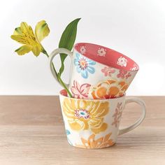 three flower patterned cups stacked on top of each other with one yellow flower in the middle