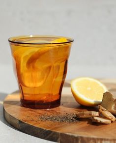 a glass of tea next to a sliced lemon on a cutting board