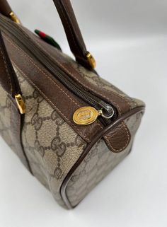 A stunning vintage Gucci Boston bag made from the beige GG canvas with brown leather trim and gold hardware. Inside the bag is lined with a beige soft lining and there is a zipped pocket for valuables. This bag is in good vintage condition, there is some deterioration to the inner lining. A true collectors item! Gucci Boston Bag, Boston Bag, Vuitton Bag, Diaper Backpack, Bags Designer Fashion, Exclusive Bag, Baby Bag, Brunei, New Bag