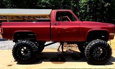 a red pick up truck parked on top of a driveway