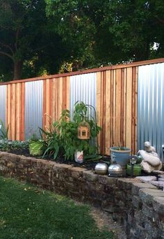 an outdoor garden area with various plants and potted plants in front of a fence