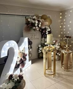 a birthday party with balloons and lights on the wall, two cake stands and flowers in vases