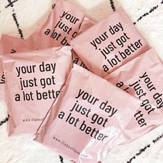 four pink packets with black writing on them sitting on a bed next to each other