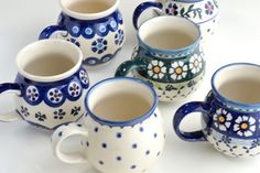 six ceramic coffee mugs with blue and white designs on the sides, all lined up