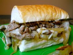 a close up of a sandwich on a green plate with onions and meat in it