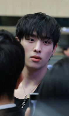 a young man with black hair and piercings looking at another person's face