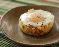 an egg on top of some kind of food in a brown bowl with a green and red table cloth