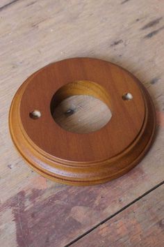 a wooden toilet seat cover on top of a wooden floor with screw holes in the middle