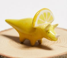 a small yellow animal figurine sitting on top of a piece of wood