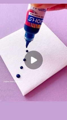 someone is painting something white with blue dots on it and using a glue bottle to paint the paper