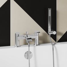 two chrome faucets are attached to the side of a white bathtub in front of a black and beige geometric wall