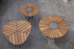 three wooden tables sitting next to each other on top of cement floored ground,