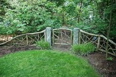 a wooden fence in the middle of a lush green park with lots of trees and bushes