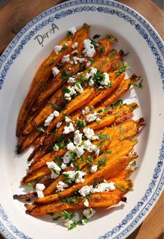 baked sweet potato wedges with feta cheese and herbs on a blue and white plate