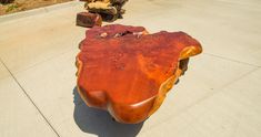 a wooden table sitting on the side of a road next to a tree trunk and another piece of wood