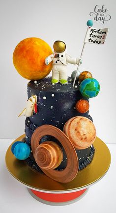 a birthday cake with an astronaut on top and space related items around the cake,