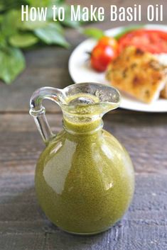 a green liquid in a glass pitcher on a table with other food items behind it