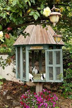 two cats sitting in a bird house surrounded by flowers