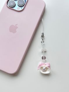 an iphone case with a cell phone charm attached to it, next to a pair of eyeglasses