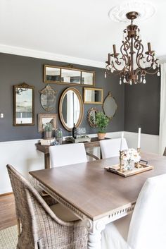 a dining room table with white chairs and a chandelier hanging from the ceiling