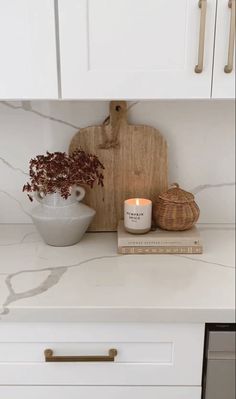 a white kitchen counter with a cutting board and candle