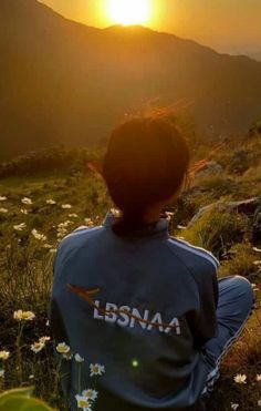 a woman sitting on top of a grass covered hillside