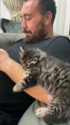 a man sitting on a couch holding a cat