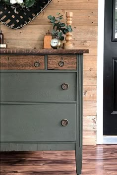 an old dresser is painted green and has some flowers on the top, along with other items