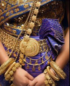 a woman in a blue and gold outfit with jewelry on her chest, wearing an elaborate necklace