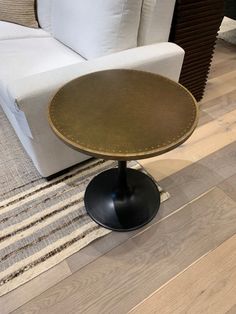 a white couch sitting next to a wooden table on top of a hard wood floor