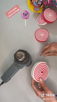 two hands are holding lollipops on top of a table with other candies