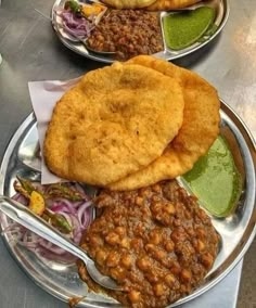 three plates filled with different types of food on top of a metal tablecloth covered table