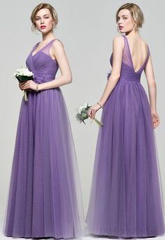 two women in long purple dresses standing next to each other and one is holding a bouquet