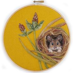 an embroidered picture of a mouse in a nest with flowers on it's side