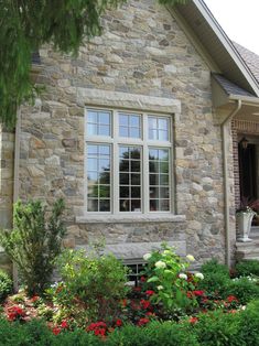 a stone house with lots of flowers in the front yard