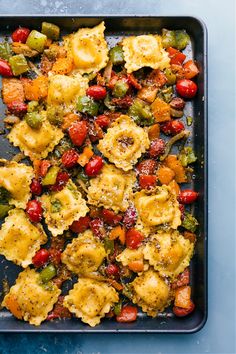 a pan filled with different types of food on top of a blue countertop next to utensils