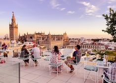 people are sitting on chairs and tables overlooking the city