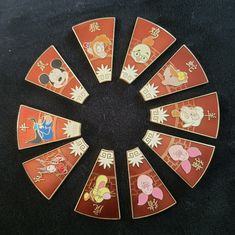 an assortment of disney pinbacks arranged in a circle on a black tablecloth