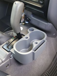 the interior of a car with an electronic device in the center console and cup holder