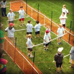 a group of people standing on top of a lush green field next to a net