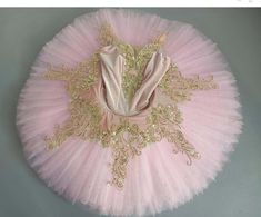 a pink tutu with gold trims on the bottom and an embroidered design on the top