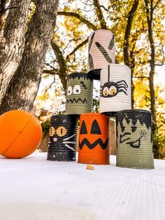 some paper cups with faces painted on them and an orange ball in the foreground