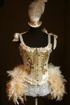 a mannequin dressed in white and gold with feathers