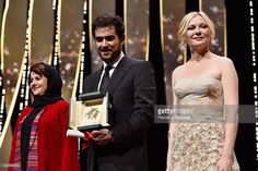 two people standing next to each other holding an award in front of a stage with lights